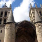 Montpellier : Cathédrale Saint-Pierre. Quatre tours s'élèvent aux angles de la nef, dont l'une fut abattue lors des mouvements iconoclastes de 1567. Le bâtiment est muni de défenses importantes, ce qui en fait une forteresse. À la fin du XVIe siècle on la surnomme d'ailleurs le « fort Saint-Pierre ». L'une des façades était couronnée par des mâchicoulis surmontés de créneaux, derrière lesquels devait courir un chemin de ronde dans l'épaisseur du mur. L'entrée est précédée d'un porche massif, composé de deux piliers cylindriques et d'une voûte reliant les piliers à la façade de l'église. Ce sont pratiquement les seuls éléments de l'architecture médiévale de la cathédrale que l'on peut encore observer aujourd'hui. L'église était composée d'un vaisseau unique, de cinq travées délimitant les chapelles latérales au nombre de quatorze. 